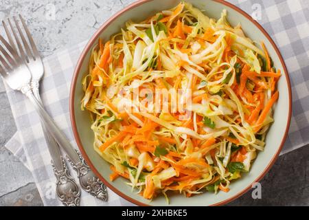 Cabbage salad with carrots dressed with vinegar and olive oil close-up in a bowl on the table. Horizontal top view from above Stock Photo