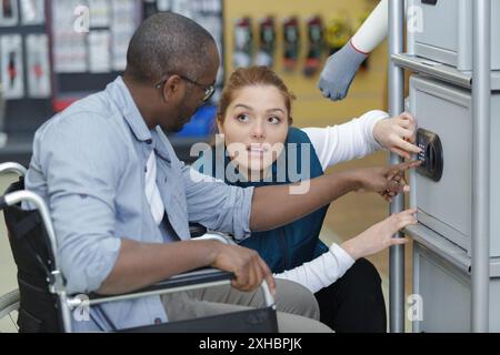 african american male sits at workplace in wheelchair near colleague Stock Photo