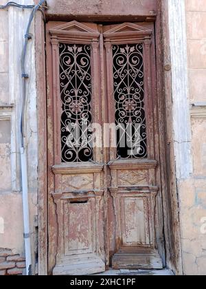 This image captures the rustic charm of a pair of weathered wooden doors, each adorned with intricate ironwork and patterns. The doors stand as a test Stock Photo