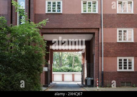 The facade of a brick building featuring symmetrical windows with white frames. The structure has alternating layers of red bricks. Stock Photo