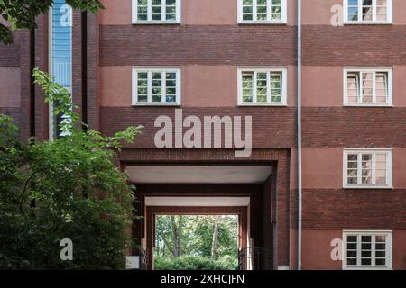 The facade of a brick building featuring symmetrical windows with white frames. The structure has alternating layers of red bricks. Stock Photo