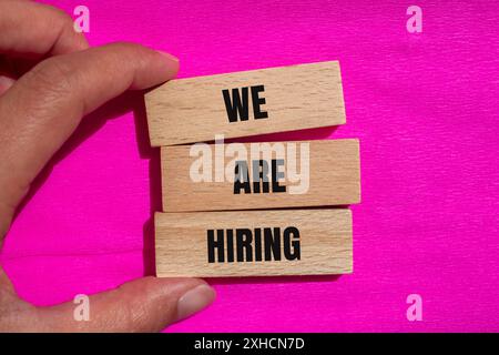 We are hiring words written on wooden blocks with pink background. Conceptual we are hiring symbol. Copy space. Stock Photo