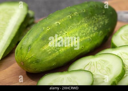 Organic Cucumber and slices on wooden cutting board. Cucumis sativus Stock Photo