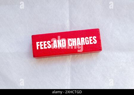 Fees and charges words written on red wodoen block with white background. Conceptual fees and charges symbol. Stock Photo