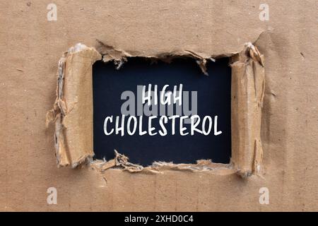 High cholesterol message written on ripped cardboard paper with black background. Conceptual high cholesterol symbol. Copy space. Stock Photo