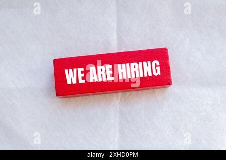 We are hiring words written on red wodoen block with white background. Conceptual we are hiring symbol. Copy space. Stock Photo