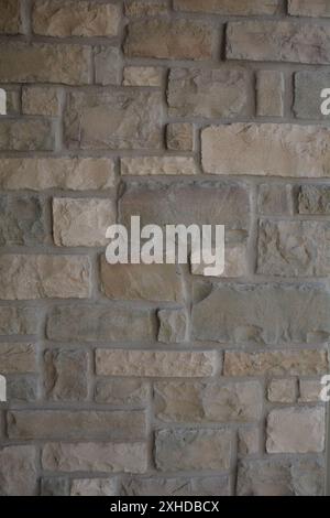 Close up of a square cut gray stone wall with elements of brown, yellow, orange, and cream earth tones. Stock Photo