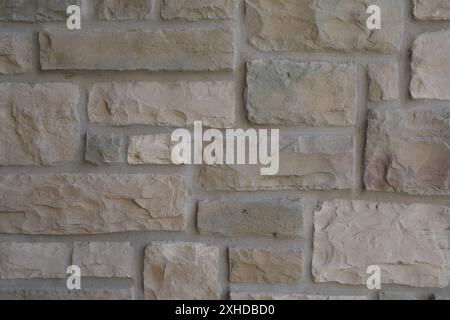 Close up of a square cut gray stone wall with elements of brown, yellow, orange, and cream earth tones. Stock Photo