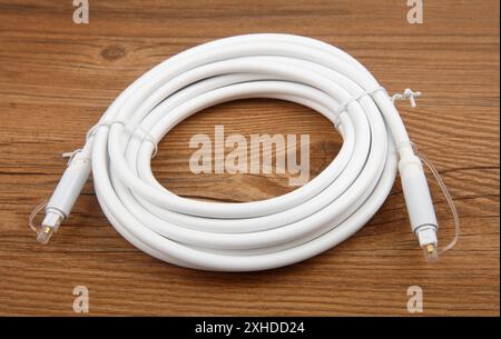 Coiled optical Audio Cable on wooden background Stock Photo