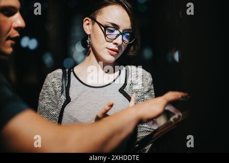 Business meeting at night with two colleagues discussing work on a tablet Stock Photo