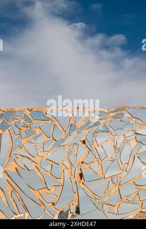 Abandoned simple building. Outer wall covered by a mosaic made of pieces of mirror, reflecting sky and  clouds, which is also above in reality. Lanzar Stock Photo