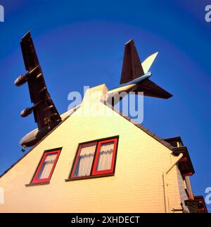 Large jet aircraft on landing approach over suburban housing against clear blue sky Stock Photo