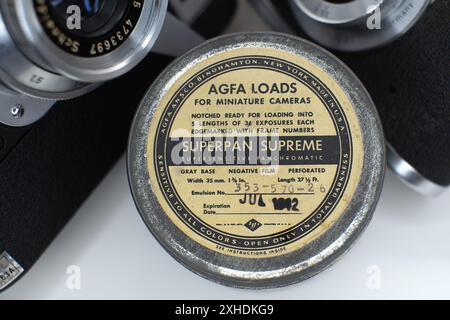 Tin box for negative film roll, historical with two historical cameras in the background. Stock Photo