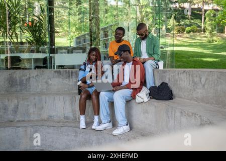 Company of happy black students studying together sitting on staircase on university campus Stock Photo