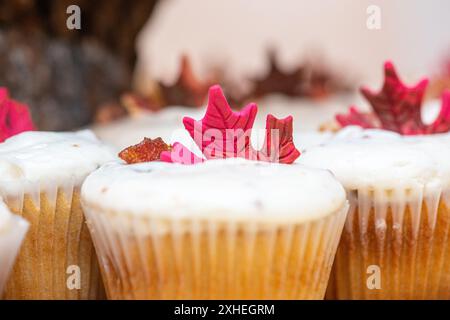 Yummy vanilla cupcackes on wood plate Vanilla cupcakes with vanilla icing and red candy leaves decor Stock Photo