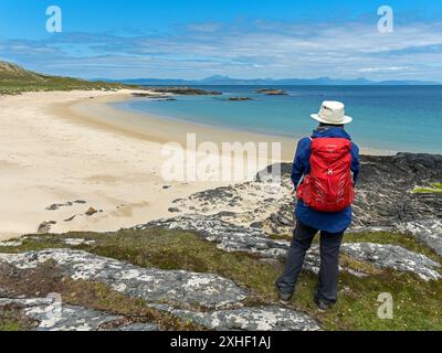 Female tourist / holidaymaker / walker / looking at the beautiful sands of Balnahard beach on the Hebridean Island of Colonsay in June, Scotland, UK Stock Photo