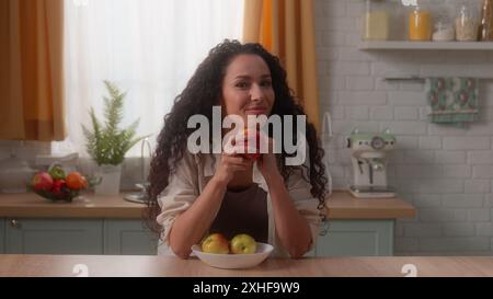 Hispanic woman Latina girl Caucasian female housewife homeowner home kitchen happy smiling toothy at camera portrait holding vitamin healthy apples Stock Photo