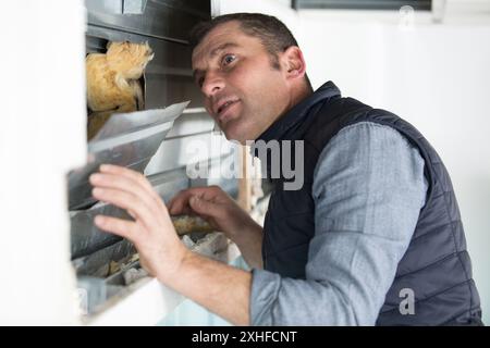 smiling man is fixing a window using a screwdriver Stock Photo