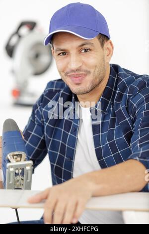 man carpenter cuts a wooden beam using an electric jigsaw Stock Photo