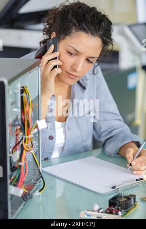 woman trying to repair computer with phone support Stock Photo
