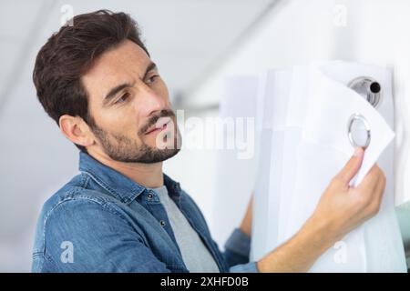 young man installing curtains over window Stock Photo