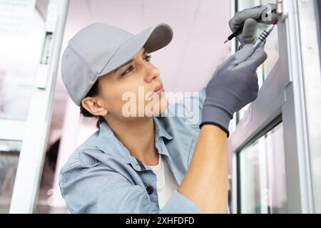 happy female builder using a screwdriver on a door Stock Photo
