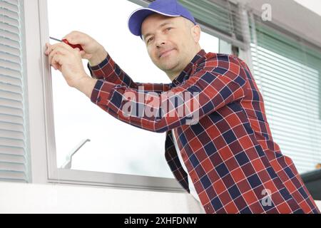 worker fasten the handle to a plastic window Stock Photo
