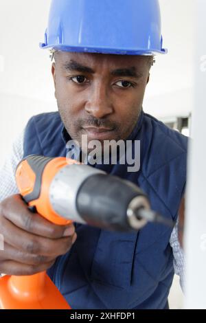 mixed race builder using cordless drill Stock Photo
