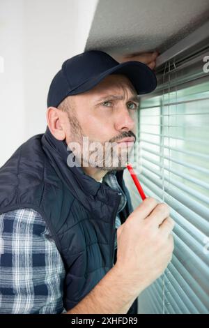 male contractor installing window blinds Stock Photo