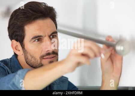 worker installing window curtain rod on the wall Stock Photo