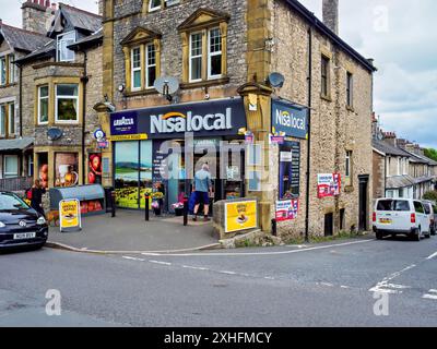 Arnside Cumbria UK. Charming neighbourhood Nisa grocery store on a street corner, with stone architecture and various products displayed outside. Stock Photo