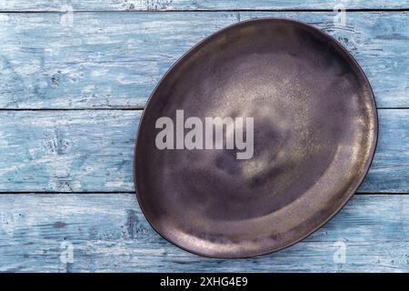 Empty black irregular plate on blue background. Top view, with copy space Stock Photo