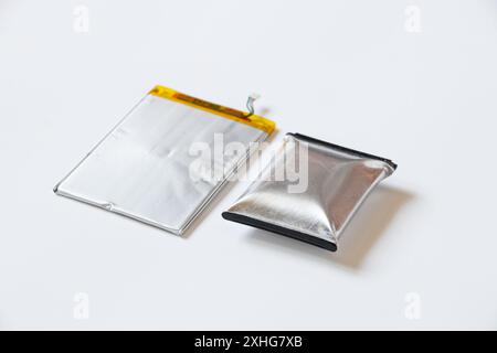 A telephone battery that is swollen from overheating lies on a white background, the phone battery is inflated Stock Photo