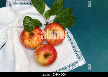 Apples on a white napkin on a turquoise background with space for text. Simple composition still life with red apple. Stock Photo