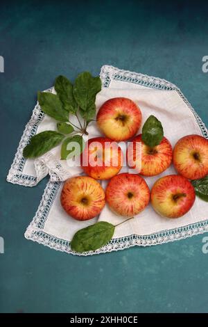 Apples on a white napkin on a turquoise background with space for text. Simple composition still life with red apple. Stock Photo