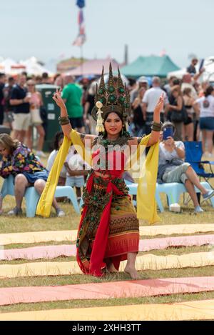 Lady dressed in traditional clothing performs a dance routine for spectators at the Thai food and craft festival in Southsea.  July 2024 Stock Photo