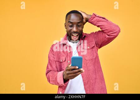 Excited Black man looking at smartphone with wow reaction isolated on yellow. Stock Photo