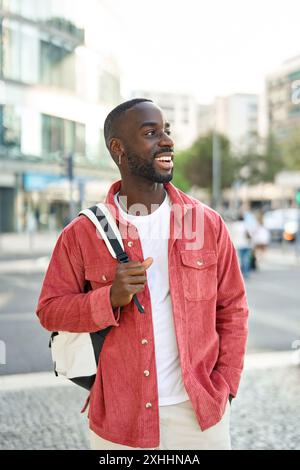 Happy young African Black man traveler standing on street looking away. Vertical Stock Photo