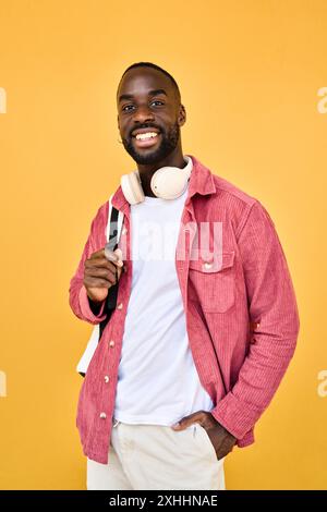 Happy young African man student standing isolated on yellow background. Stock Photo