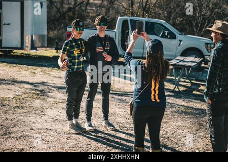 Two young men posing for a photo with medals while a woman takes their picture outdoors on a sunny day Stock Photo