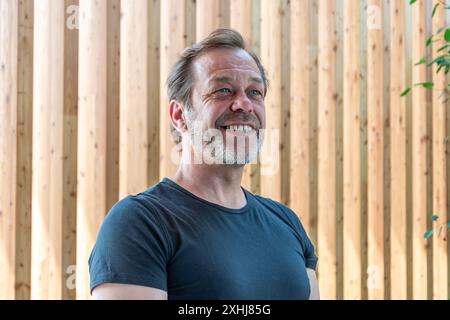 Elderly stylish man with beard 50-55 years old laughing on textured wooden background. Stock Photo