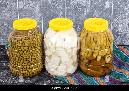 Pickled cucumbers, crushed green olives and feta cheese prepared in brine in a five kilogram plastic drum. Food concept. Stock Photo