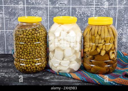 Pickled cucumbers, crushed green olives and feta cheese prepared in brine in a five kilogram plastic drum. Food concept. Stock Photo