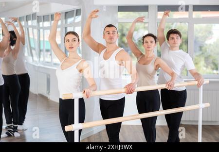 Group mastering third position at barre in classical ballet studio Stock Photo