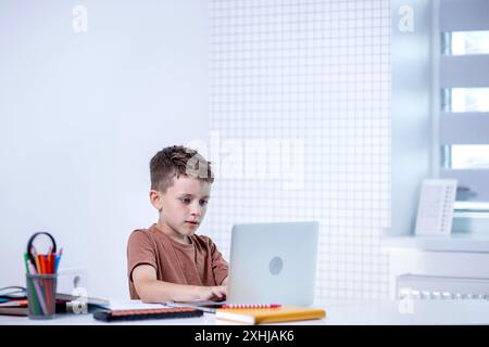 Distance learning online education. A schoolboy is studying at home using a laptop. Home distance learning. Stock Photo