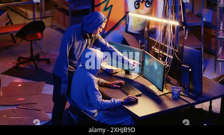 Hackers in underground bunker working together to take advantage of security breach after gaining unauthorized access to system. Rogue programmers hacking network to steal government data Stock Photo