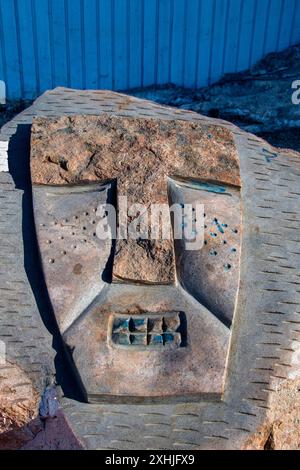 Stone carvings of masked faces on a rock at Inuit sculpture park by the Four Corners in Iqaluit, Nunavut, Canada Stock Photo