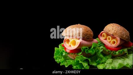 Sandwich featuring lettuce, tomato, ham and cheese isolated on black background Stock Photo