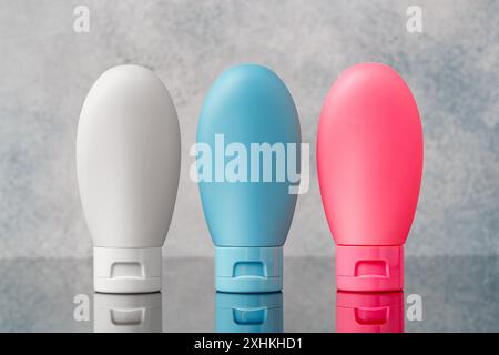 Three Plastic Bottles With White, Blue, and Pink Labels on a Grey Background: Three Plastic Bottles Stand in a Row on a Grey Background. Stock Photo