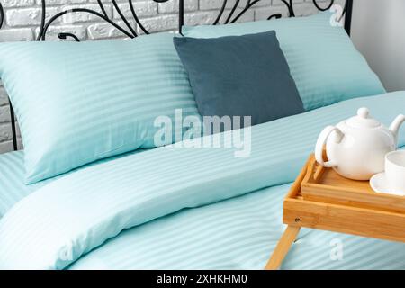Wooden Breakfast Tray With Teapot, Grapes, and Cup on a Blue Bed Stock Photo